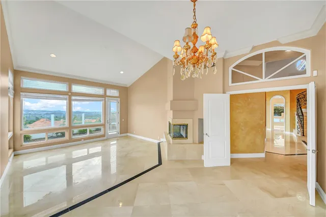 a large white kitchen with granite countertop a sink and white cabinets next to a window