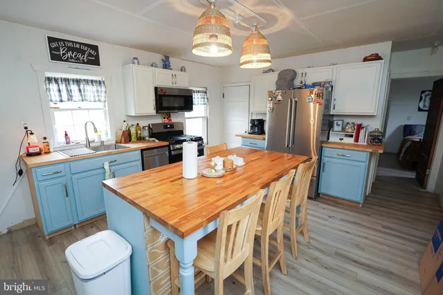 a kitchen with stainless steel appliances granite countertop a stove top oven a sink dishwasher a dining table and chairs with wooden floor