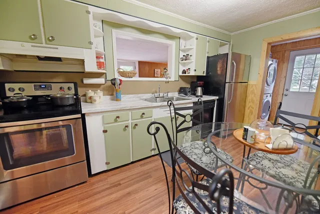 a kitchen with stainless steel appliances granite countertop a stove a refrigerator a sink dishwasher a dining table and chairs with wooden floor