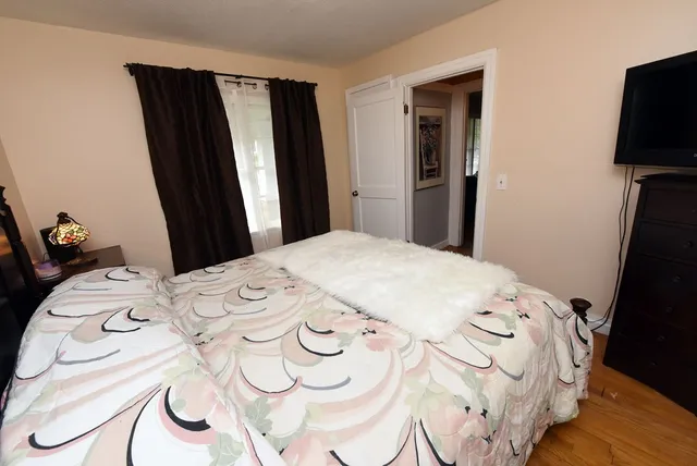 a bedroom with a bed and a flat tv screen on the dresser