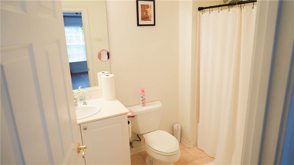3275 Lenox Road Northeast, Unit 107 Atlanta, GA 30324 - Photo 16 of 18 a white toilet sitting next to a shower curtain