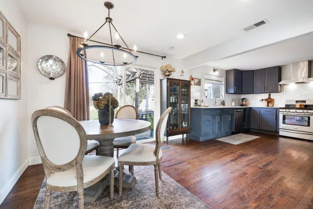 a open kitchen with stainless steel appliances granite countertop a stove a refrigerator a kitchen island a dining table and chairs with wooden floor