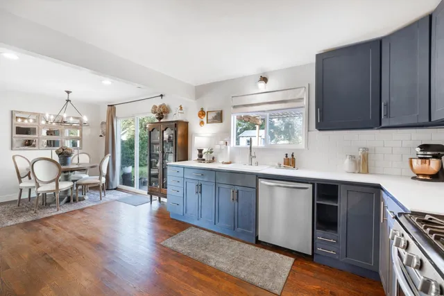 a kitchen with stainless steel appliances granite countertop a sink dishwasher stove and wooden cabinets with wooden floor