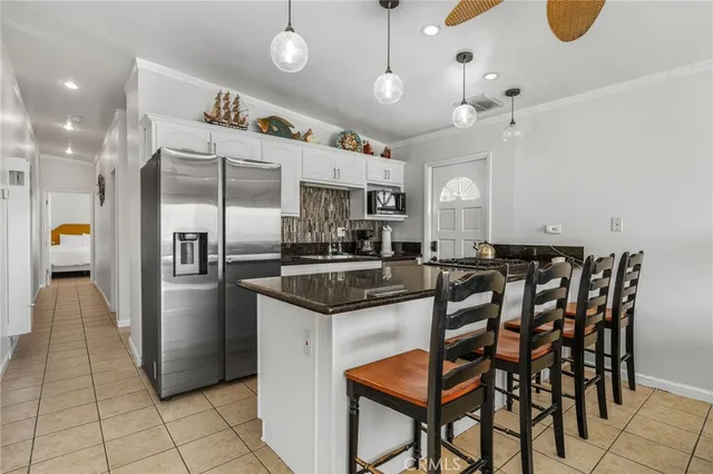 a kitchen with stainless steel appliances granite countertop a sink a stove a refrigerator and island with wooden floor