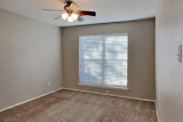 an empty room with a window and a ceiling fan
