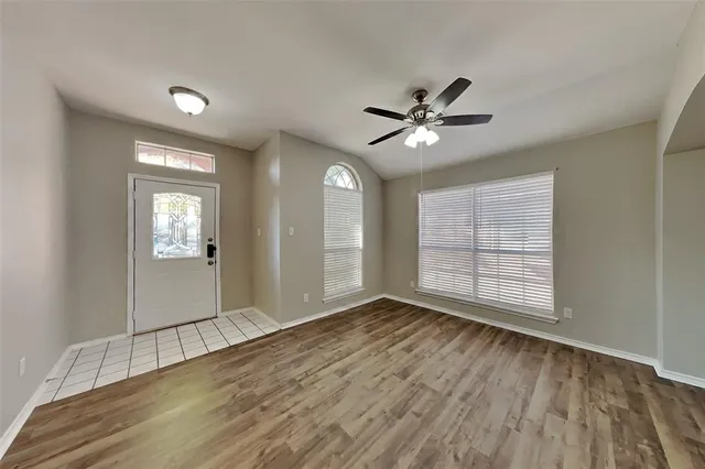 a view of an empty room with a window and wooden floor
