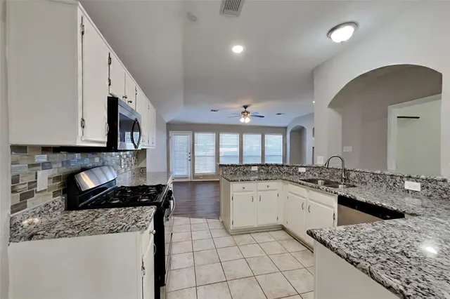 a kitchen with a sink a stove top oven and cabinets