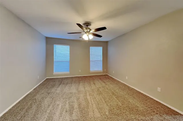 a view of an empty room with a ceiling fan and window