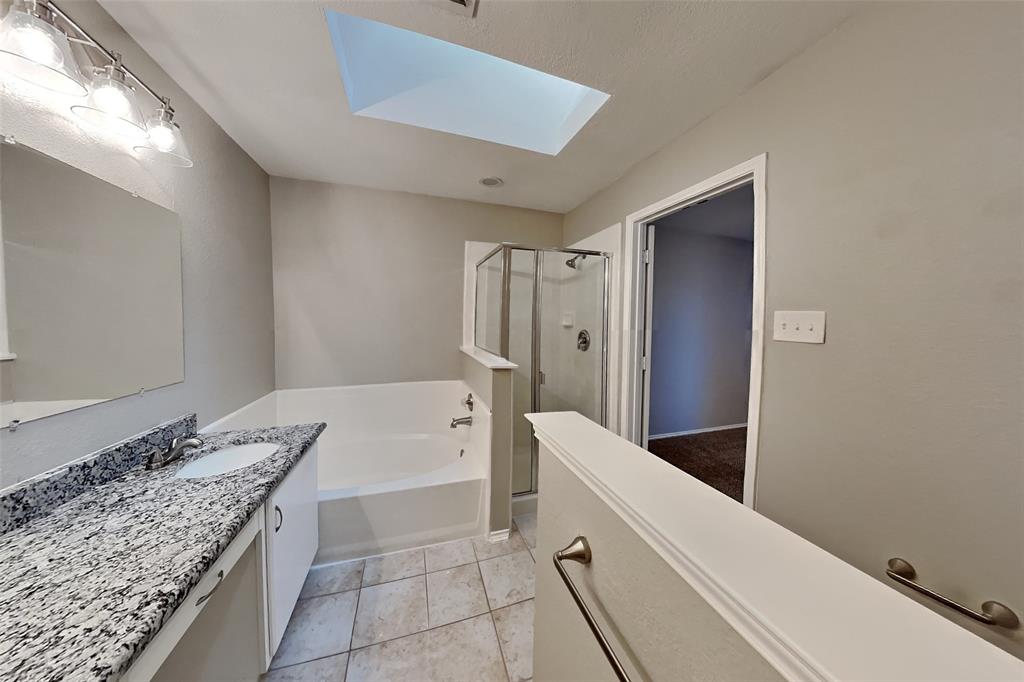 7709 Harbor Drive Rowlett, TX 75088 - Photo 9 of 19 a bathroom with a granite countertop sink a bathtub and shower