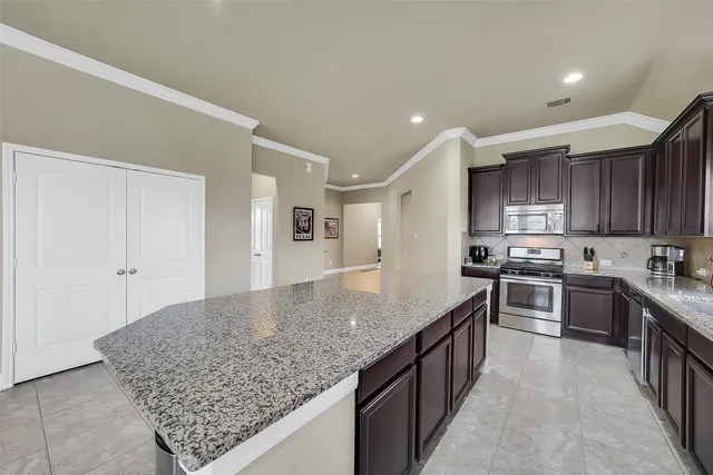 a kitchen with stainless steel appliances granite countertop a stove a sink and a refrigerator