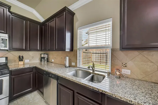 a kitchen with granite countertop a sink a stove and cabinets