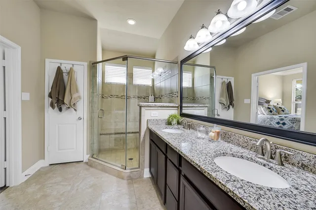 a bathroom with a granite countertop double vanity and a mirror