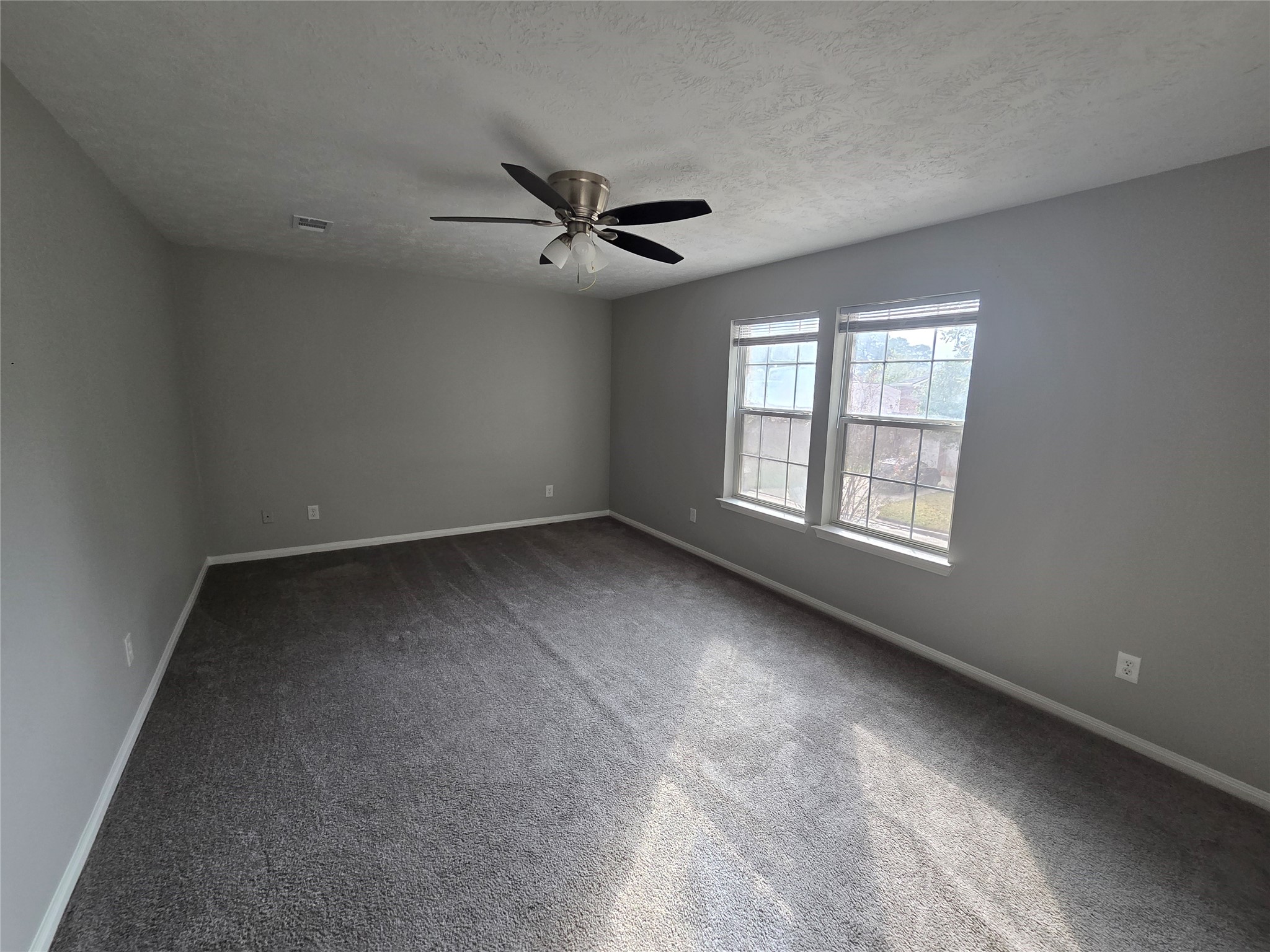 32018 Annice Lane Pinehurst, TX 77362 - Photo 12 of 19 Experience the spacious tranquility of the primary suite, featuring soft carpeting, abundant natural light through large windows, and a modern ceiling fan for ultimate comfort.