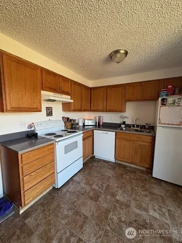 a kitchen with granite countertop a sink cabinets and stainless steel appliances