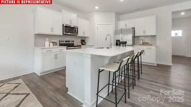 a kitchen with stainless steel appliances a microwave a stove a sink a stove a dining table and chairs