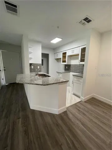 a kitchen with kitchen island granite countertop a sink cabinets and stainless steel appliances
