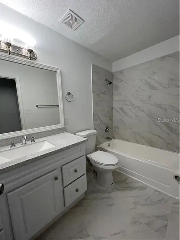 a bathroom with a granite countertop toilet a sink and a bathtub