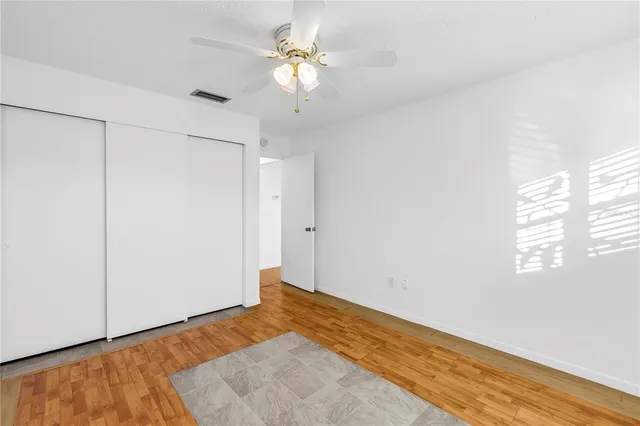 a view of a room with wooden floor and a ceiling fan