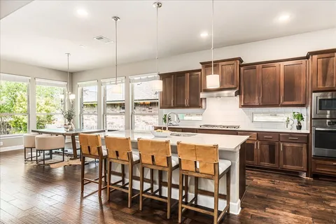 a large kitchen with kitchen island granite countertop a dining table chairs and wooden floor