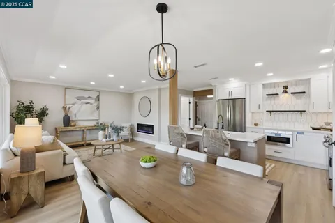 a living room with stainless steel appliances furniture a rug and kitchen view