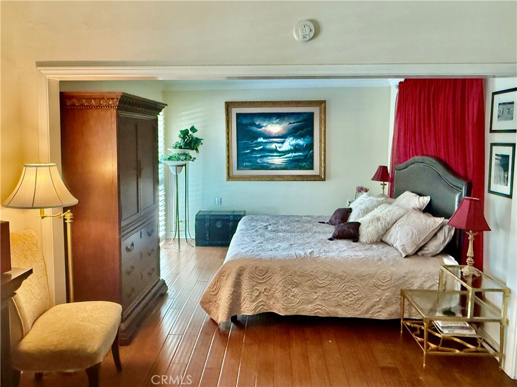 199 Avenida Majorca, Unit C Laguna Woods, CA 92637 - Photo 16 of 30 a bedroom with a bed and a lamp on table with wooden floor