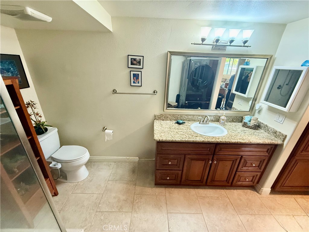 199 Avenida Majorca, Unit C Laguna Woods, CA 92637 - Photo 21 of 30 a bathroom with a granite countertop sink a mirror and a toilet
