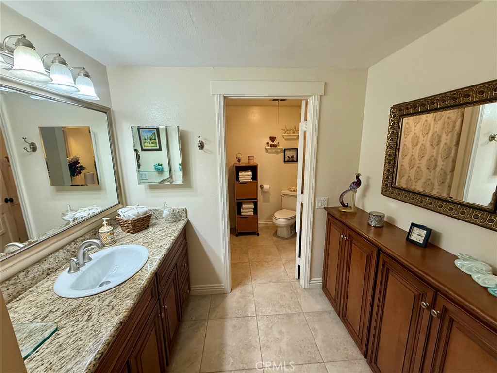 199 Avenida Majorca, Unit C Laguna Woods, CA 92637 - Photo 25 of 30 a en suite bathroom with a granite countertop sink and a mirror
