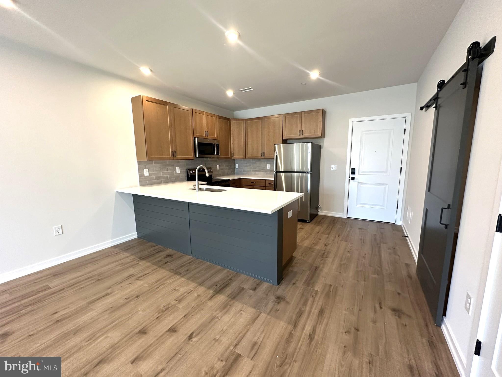 a large kitchen with a sink and dishwasher a oven with wooden floors