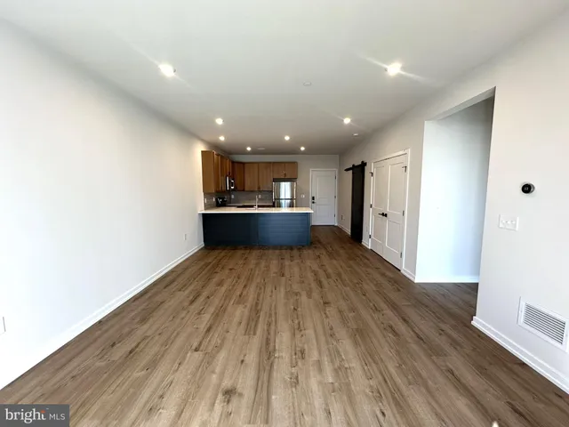 a view of a hallway with wooden floor and a room