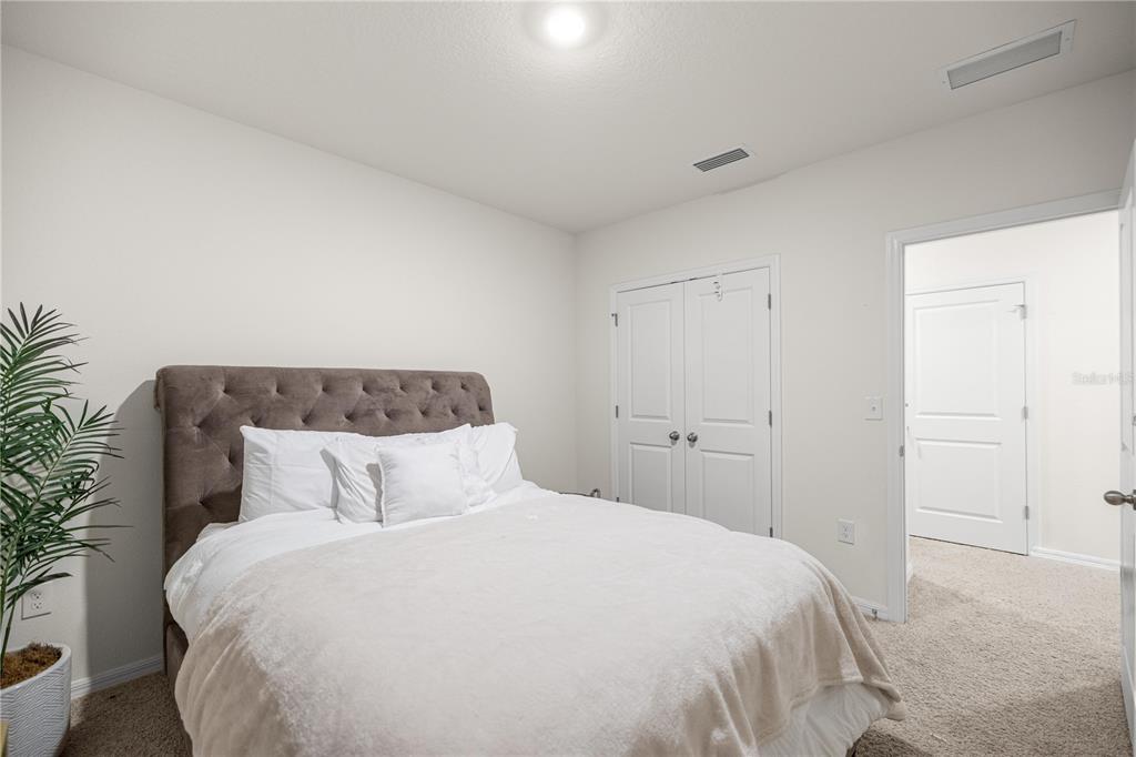 3833 Southeast 98th Place Belleview, FL 34420 - Photo 21 of 34 a bedroom with a large bed and a potted plant