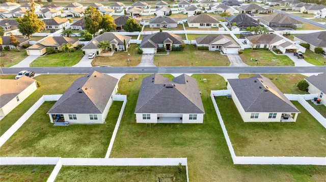 an aerial view of residential houses with outdoor space and trees