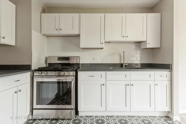 a kitchen with stainless steel appliances granite countertop a stove a white cabinet and a granite counter tops
