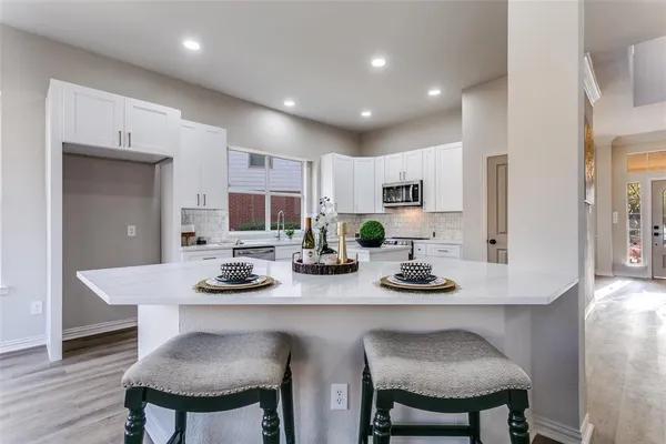 a kitchen with a dining table chairs and white cabinets