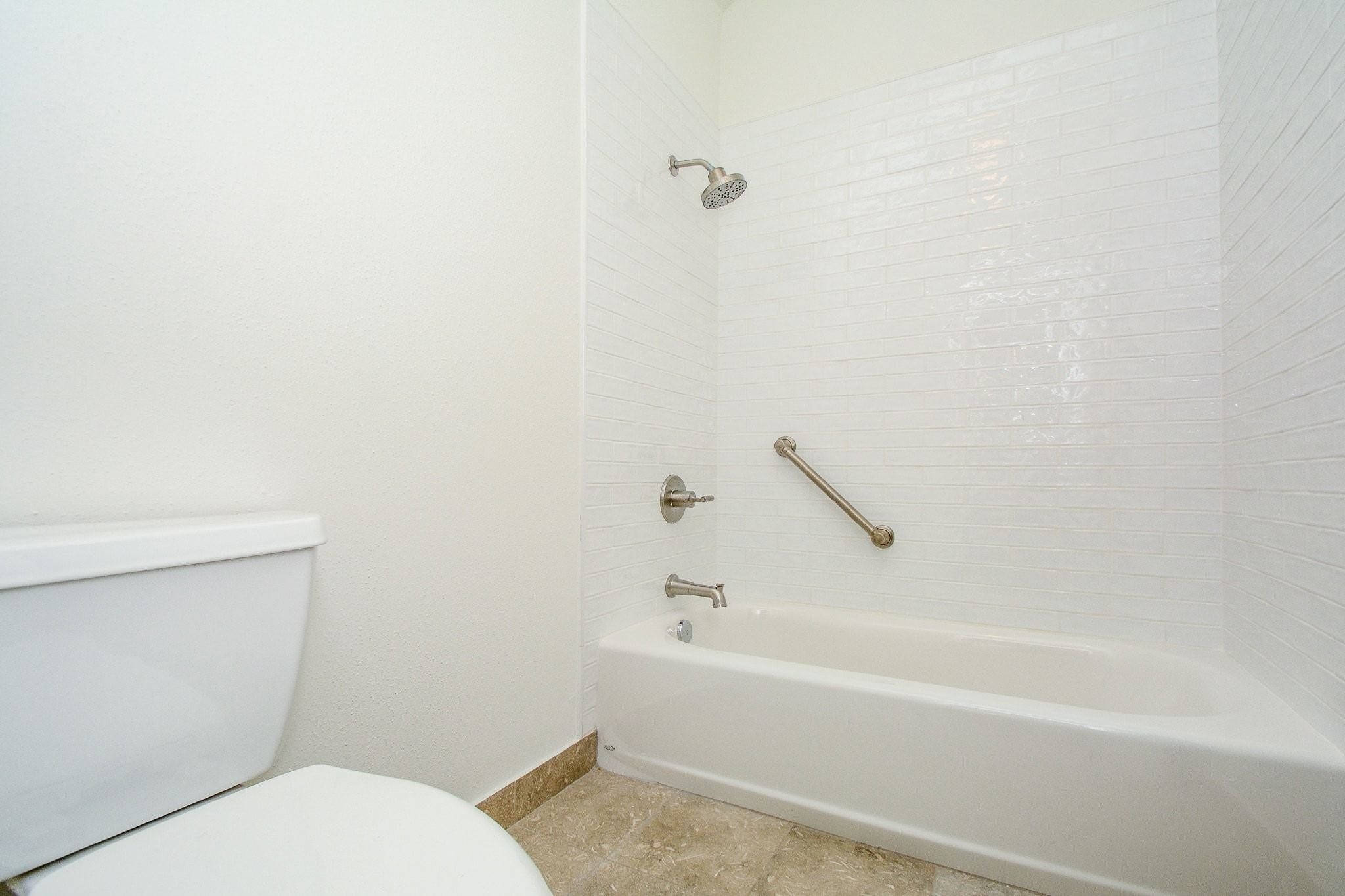820 Harold Street Houston, TX 77006 - Photo 25 of 33 The primary en suite features a tub/shower combo with floor to ceiling white subway tile, brushed nickel fixtures, and a handy grab bar.