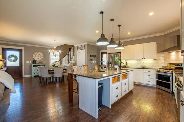 a kitchen with stainless steel appliances granite countertop wooden floors and white cabinets