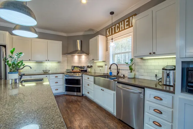 a kitchen with kitchen island granite countertop a sink cabinets and stainless steel appliances