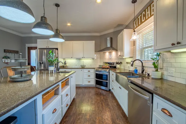 a kitchen with stainless steel appliances granite countertop a sink a stove and a wooden floors