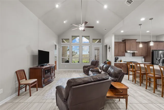 a living room with furniture a ceiling fan and a flat screen tv