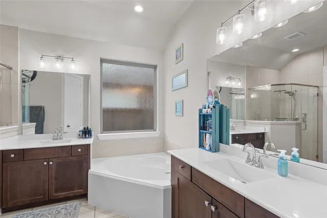 a bathroom with a tub a sink double vanity and shower