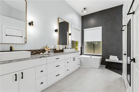 a spacious bathroom with double sink large mirror and a toilet