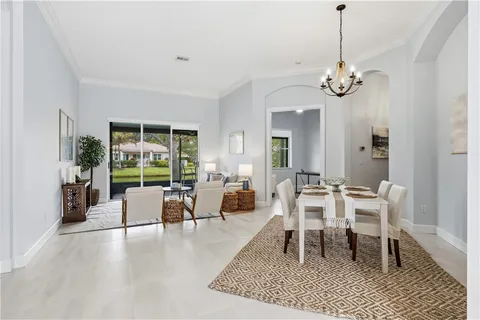 a dining room with wooden floor a chandelier a wooden table and chairs