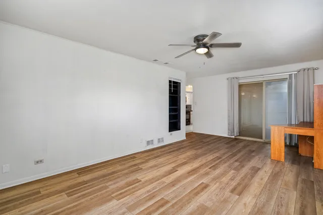 a view of empty room with wooden floor and fan