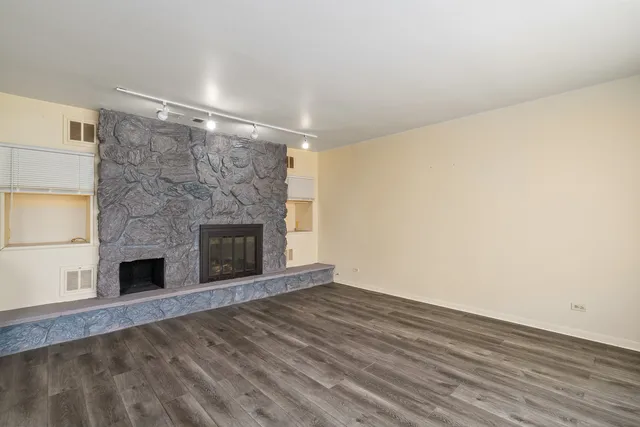 a view of empty room with wooden floor and fireplace