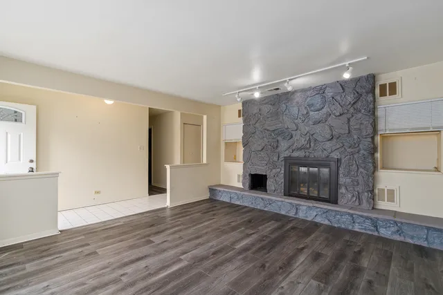 a view of an empty room with wooden floor and a fireplace