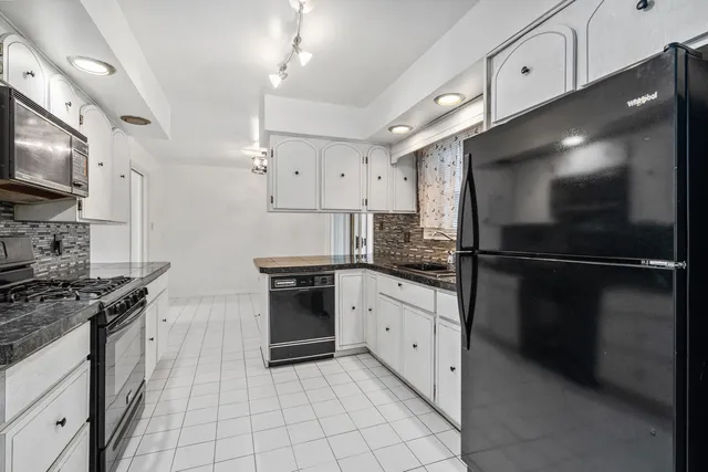 a kitchen with granite countertop a refrigerator and a stove top oven