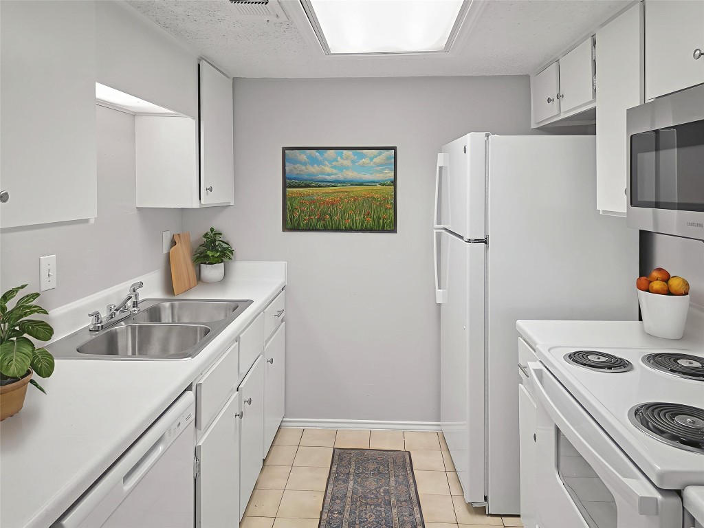 2401 Leon Street, Unit 110 Austin, TX 78705 - Photo 2 of 13 Kitchen featuring white cabinetry, white appliances, light countertops, and light tile patterned floors
