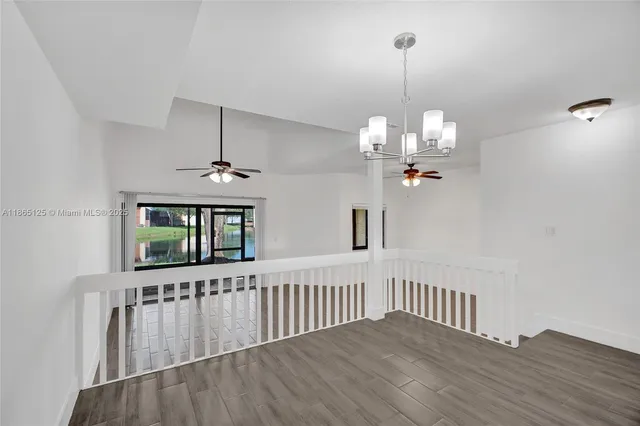 a view of a hallway with wooden floor and chandelier