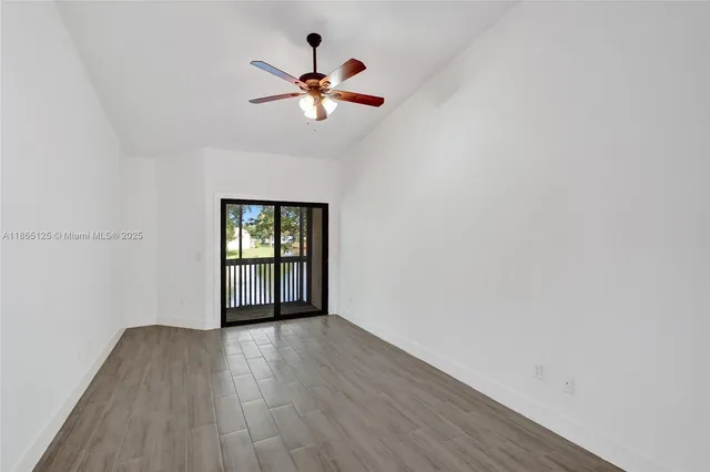 an empty room with wooden floor fan and windows