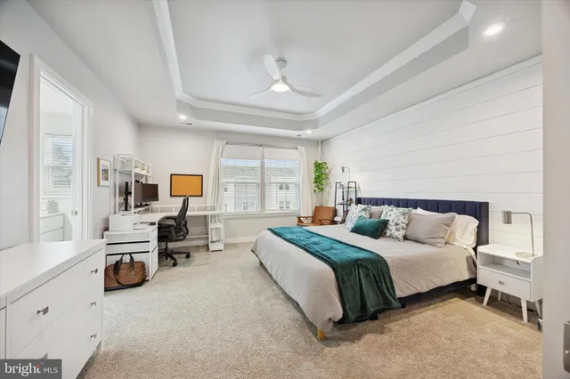 a spacious bedroom with a bed a table and large windows