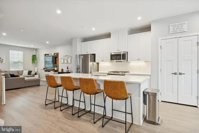 a kitchen with stainless steel appliances granite countertop a stove a sink a refrigerator and chairs